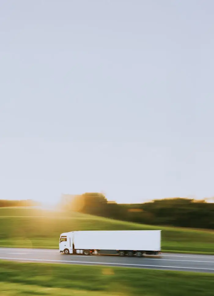 pexels photo 18290480 White cargo truck speeding through Vitebsk countryside at sunrise, symbolizing transportation and logistics.